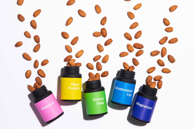 Image of five bottles labeled with nutritional benefits (Vitamin E, Plant Protein, Dietary Fiber, Unsaturated Fat, Magnesium) with almonds spilling out from each.